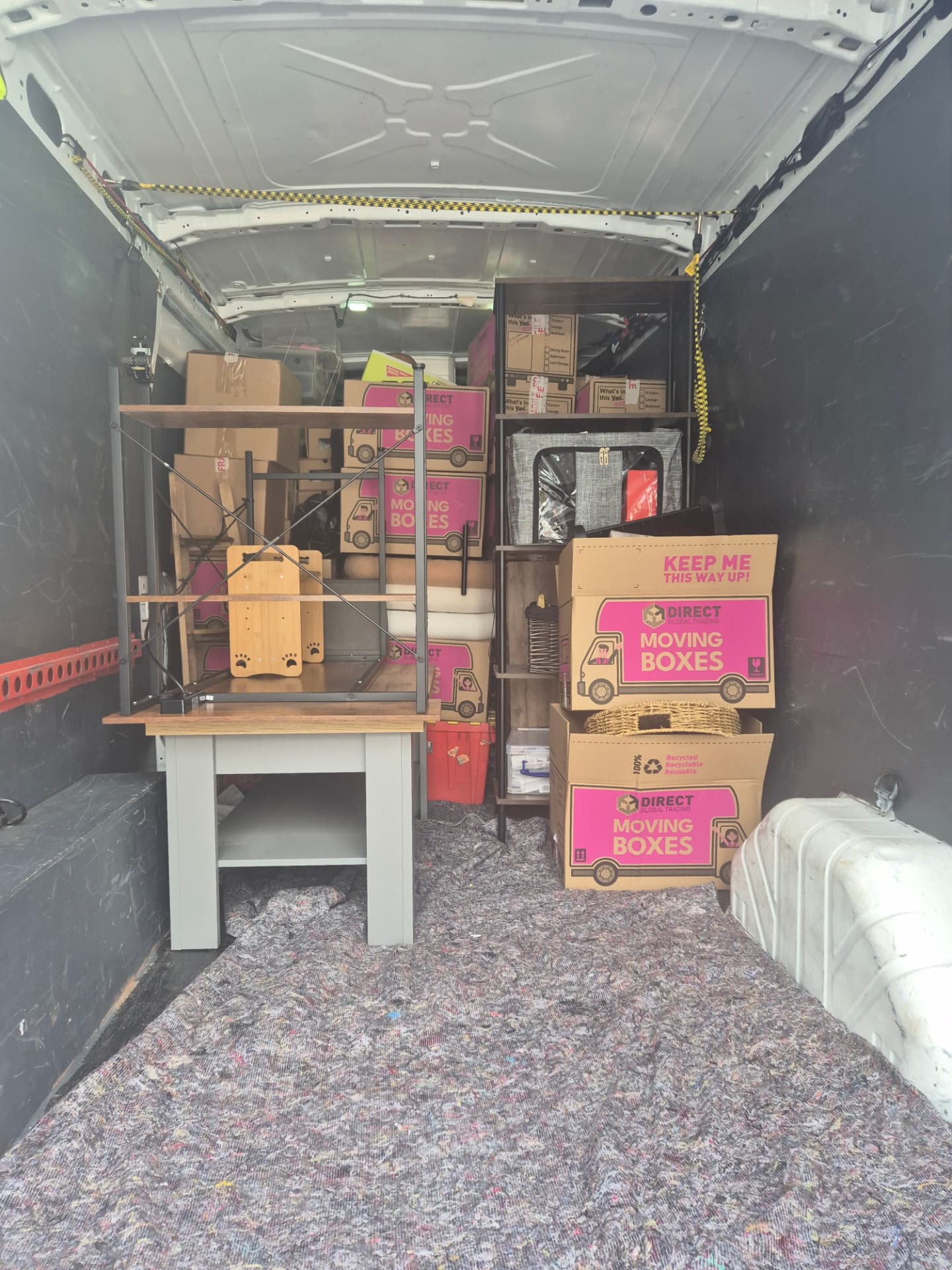 Flat-pack furniture, shelving and labelled moving boxes packed into the van for an apartment move